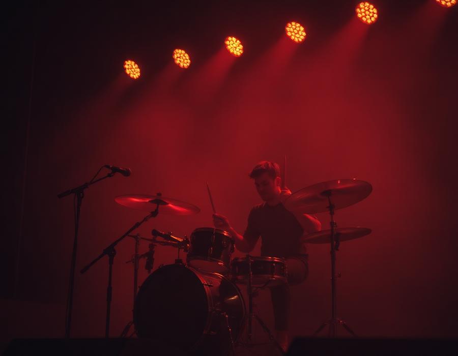 Baterista tocando en escenario con luces